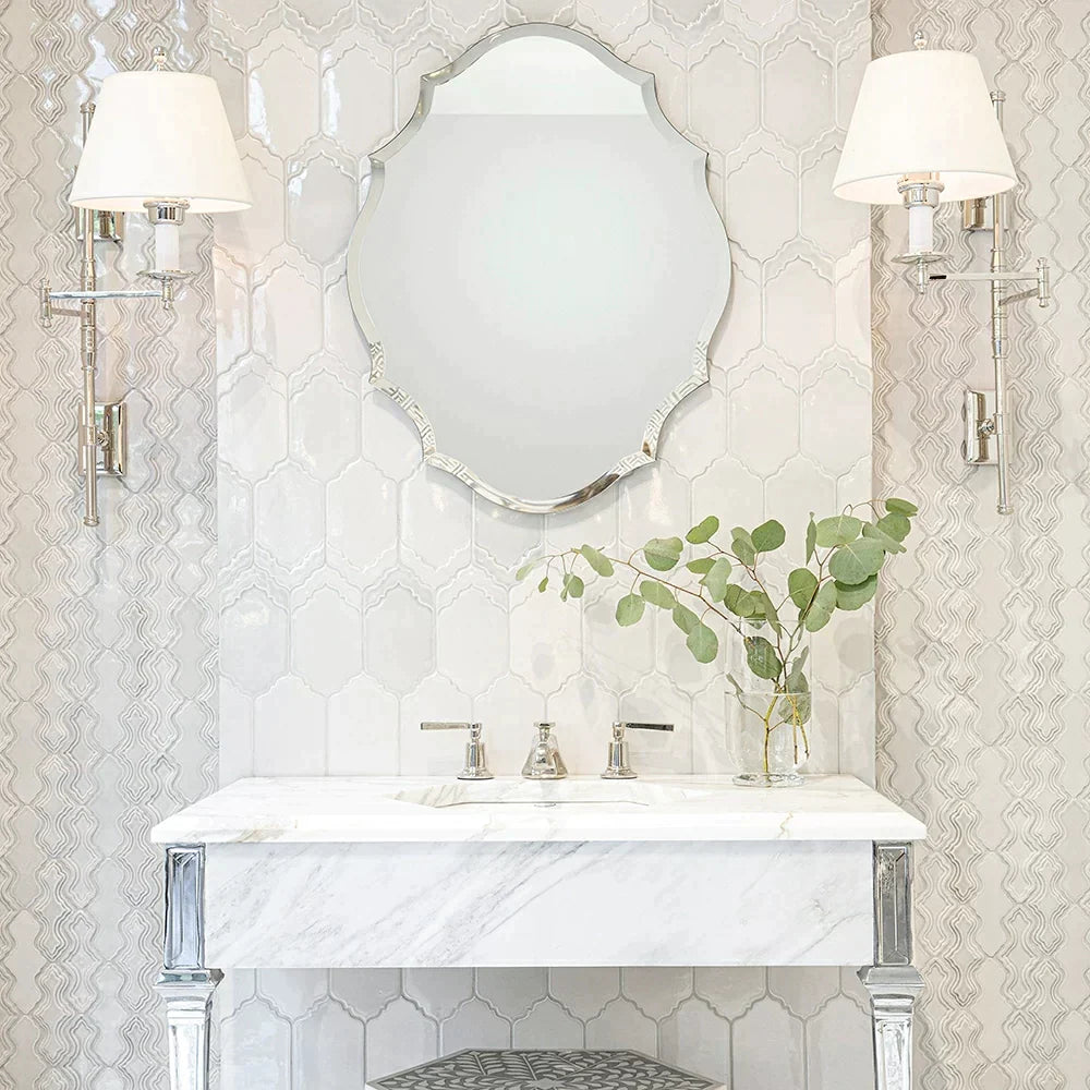 Elegant bathroom with intricate Breathe Moresque ceramic tiles, marble countertop, silver mirror, and sophisticated wall sconces.