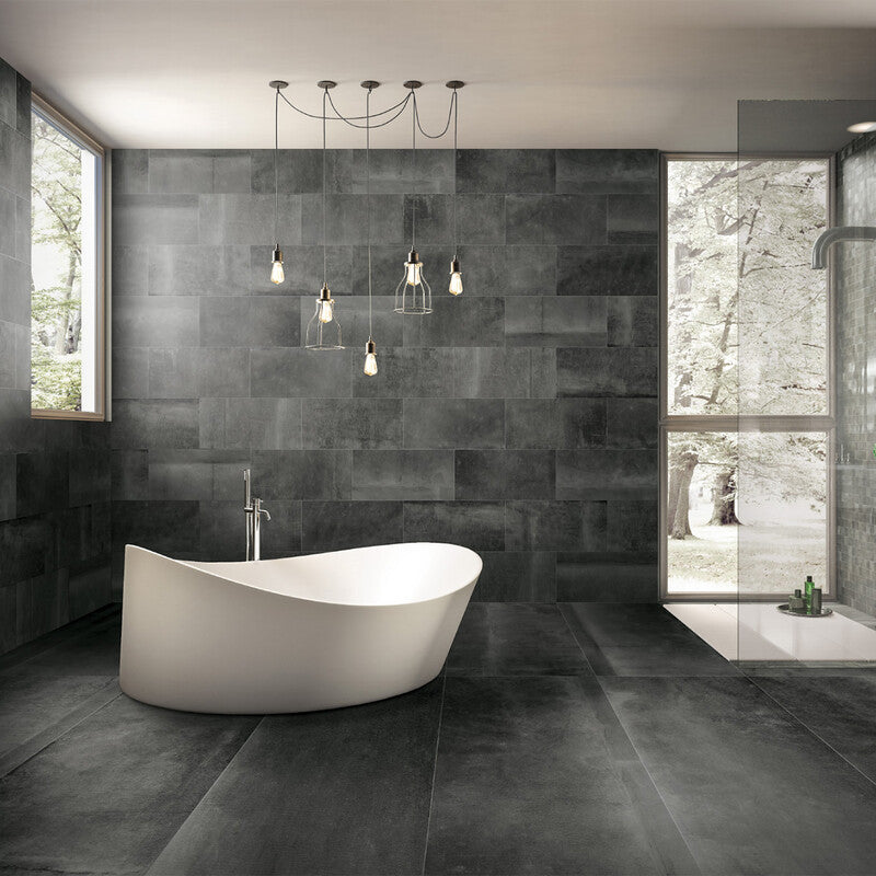 Modern bathroom with black tiles, white bathtub, pendant lights, windows, and glass-enclosed shower with outdoor view.