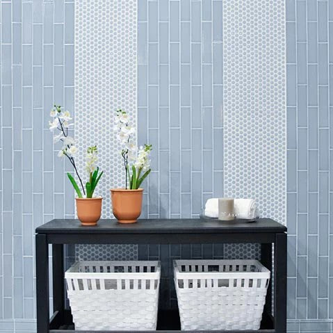 Modern entryway featuring the Adex Hampton Ceramic Tile in Stratus Gray, accentuated by a sleek black console table and vibrant potted flowers, creating an inviting and stylish atmosphere.