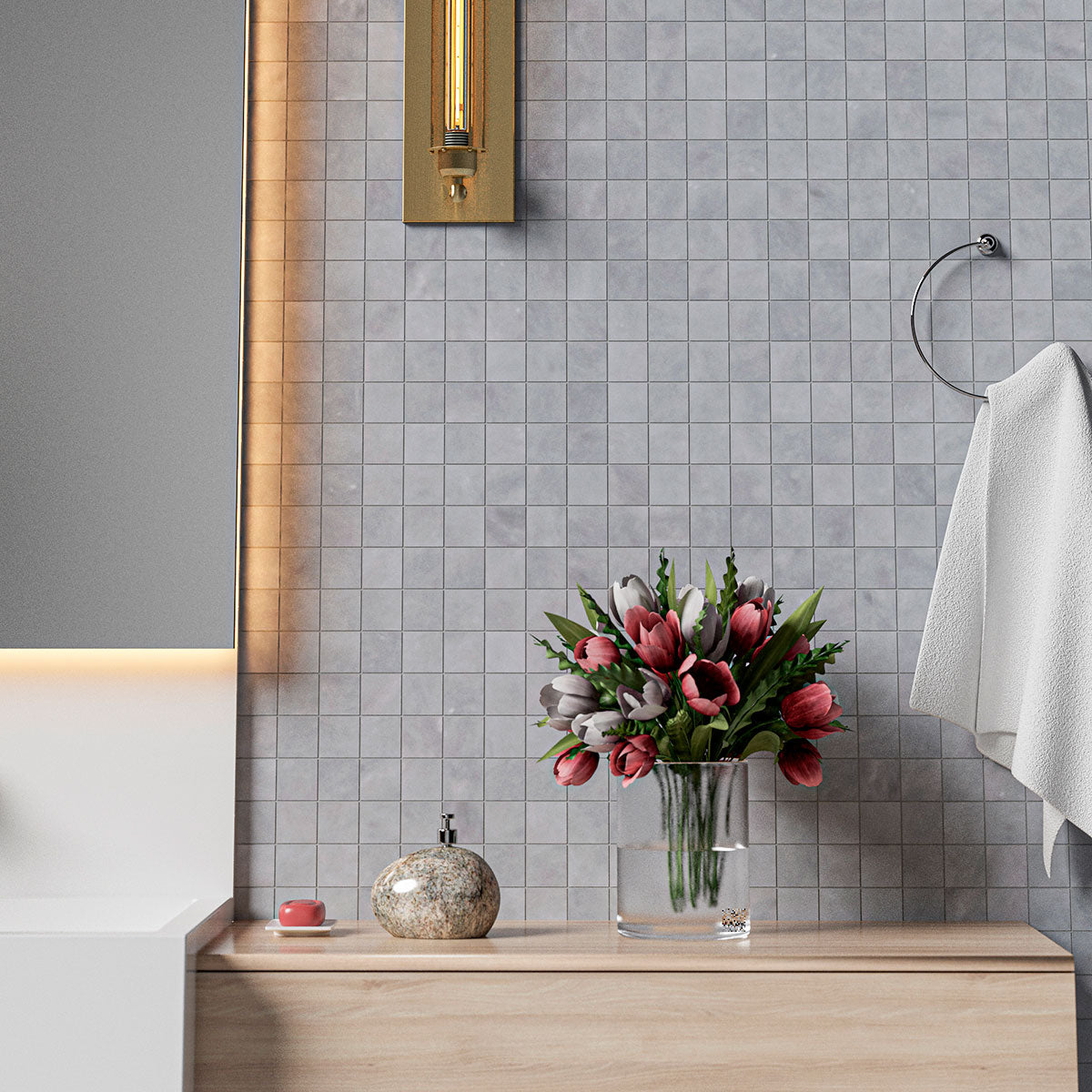 Modern bathroom with gray tile wall, wooden vanity with pink and white tulips, soap dispenser, towel ring, and gold light fixture.