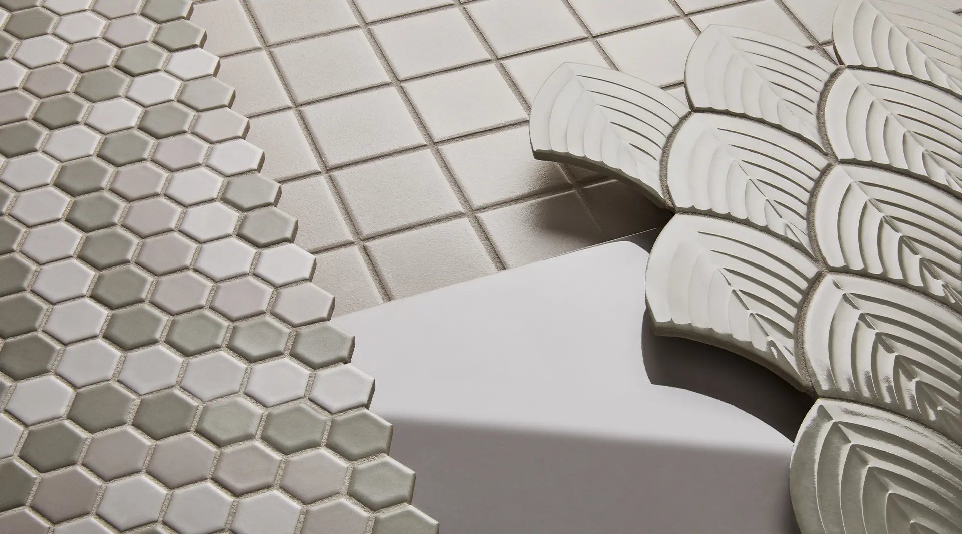 Minimalist bathroom design featuring Anatolia Soho Glazed Ceramic tiles with a subtle, geometric pattern in a calming gray hue, complemented by a contemporary round mirror and elegant bronze fixtures.