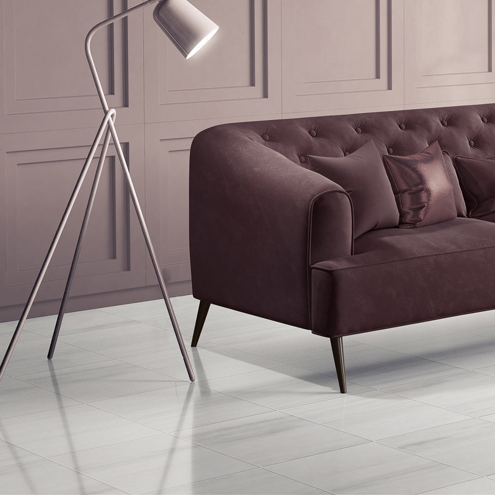 Chic living room with burgundy tufted sofa, modern lamp, and white marble flooring.