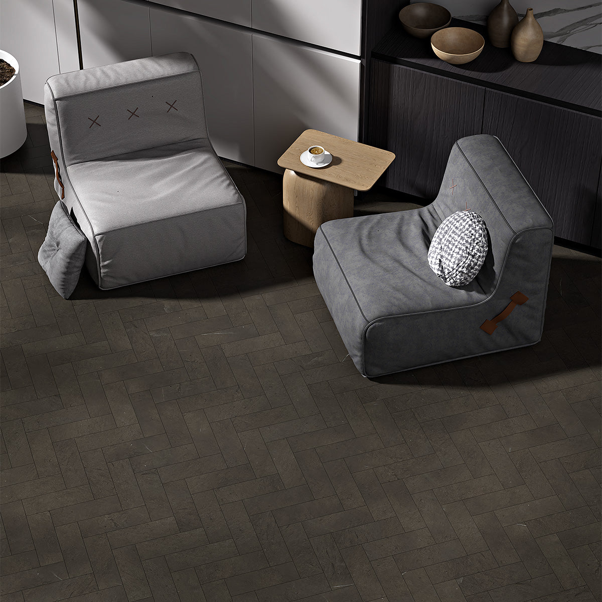 Modern living room with dark herringbone tile flooring, gray chairs, wooden table, and decor on shelf.