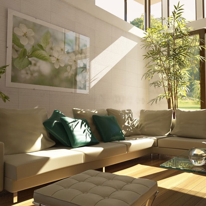 Modern living room with large windows, beige sectional sofa, light wooden flooring, potted plants, glass coffee table, wall-mounted floral artwork.