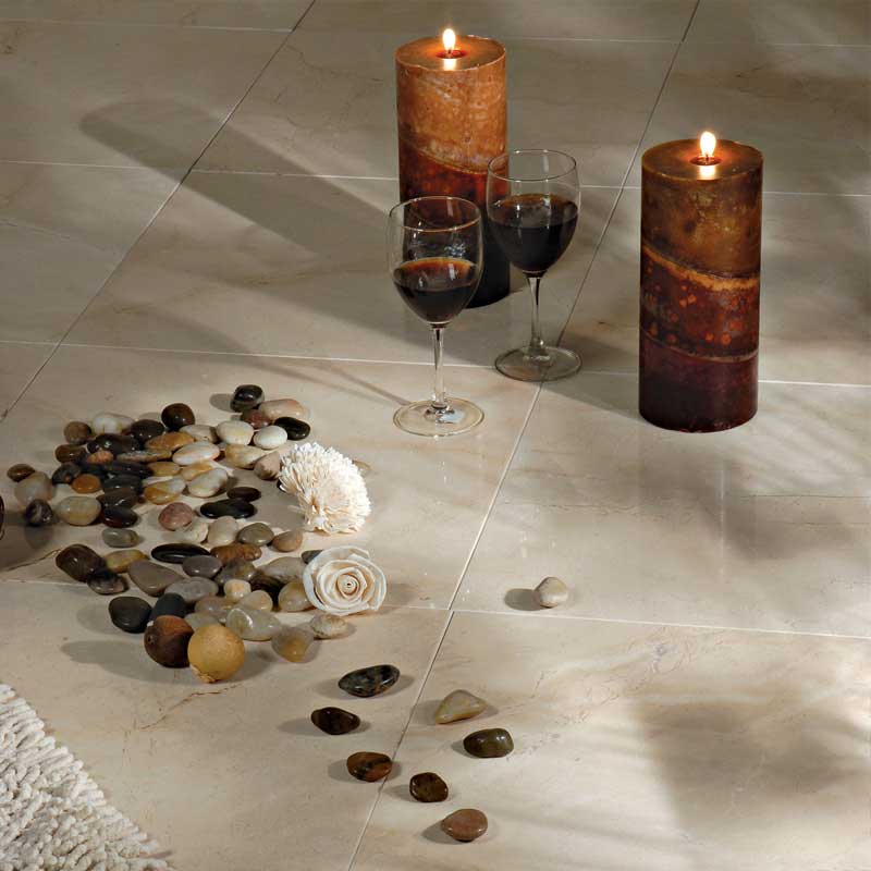 Crema marfil tiles, lit candles, red wine, pebbles, white flower, soft rug corner.