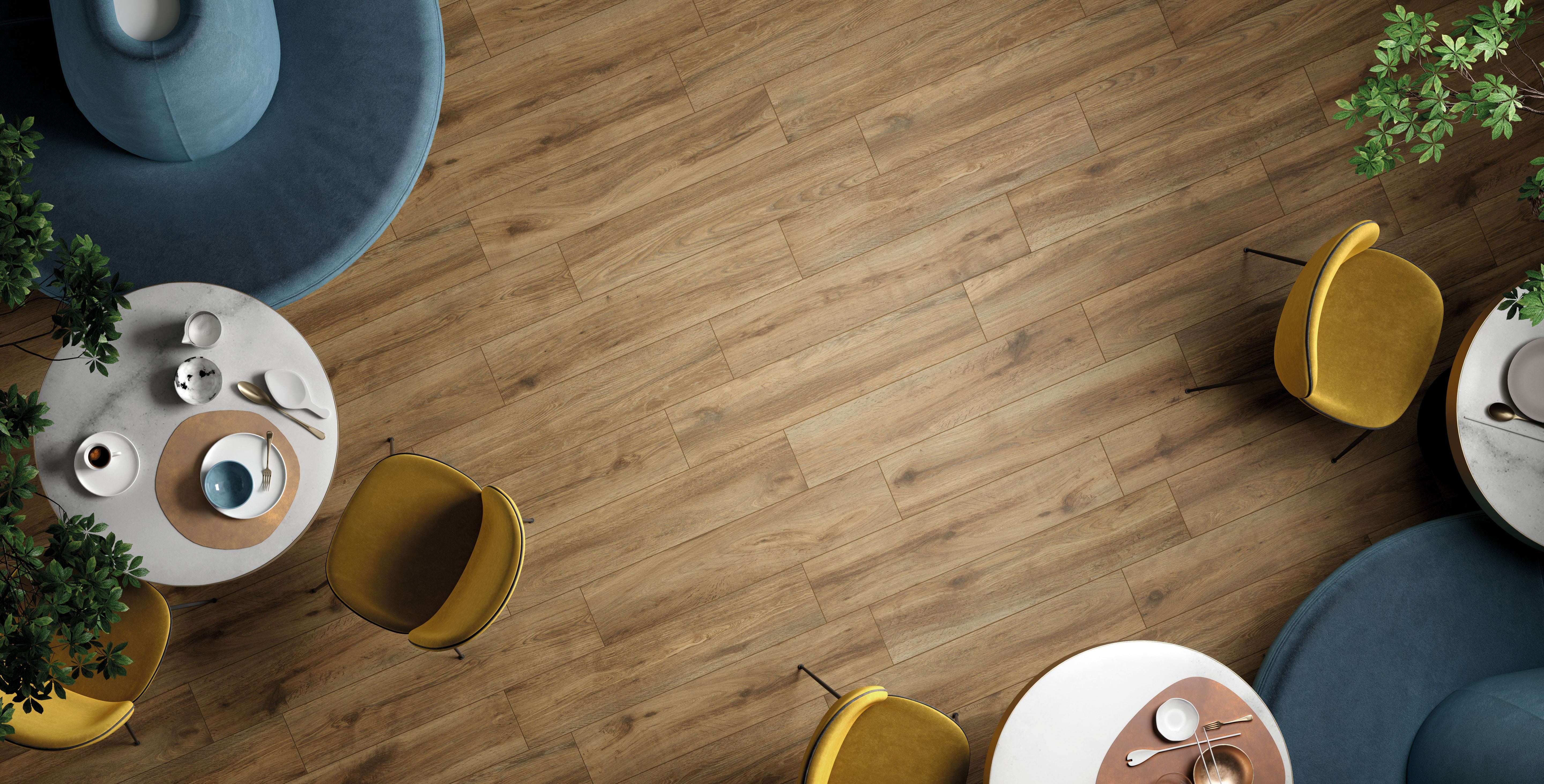 Porcelain tile flooring from the Sequoia Collection by Surface Group, featuring wood-look design in a herringbone pattern with modern furniture accents.