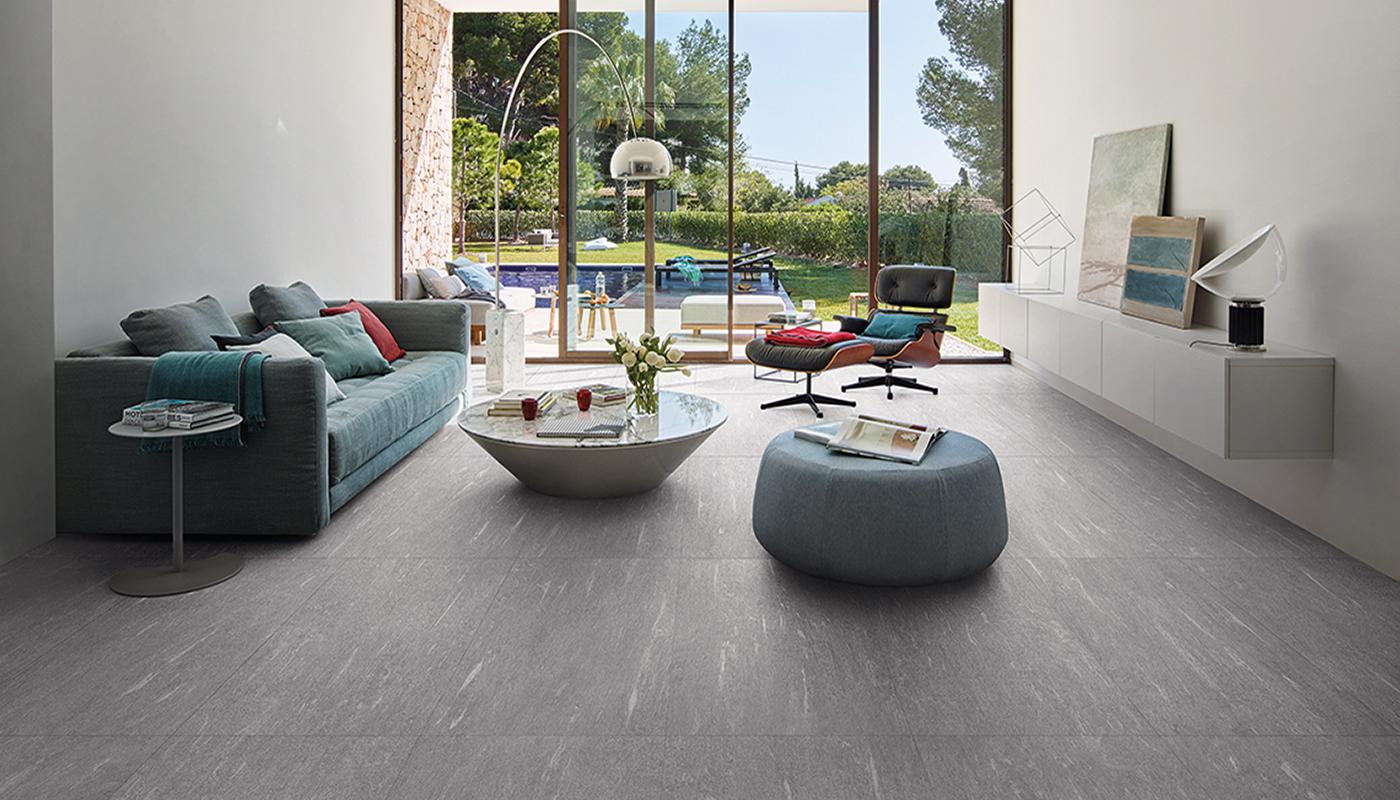 Modern living room featuring Emil Ergon Cornerstone Alpen Italian porcelain tile flooring, with stylish furniture and large window overlooking a garden.