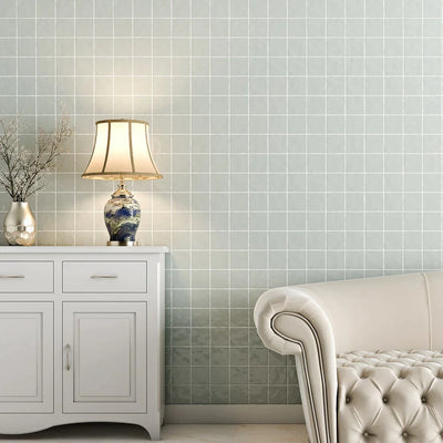 White room with leather sofa, cabinet, table lamp, vase with dried flowers against light gray tiled wall.