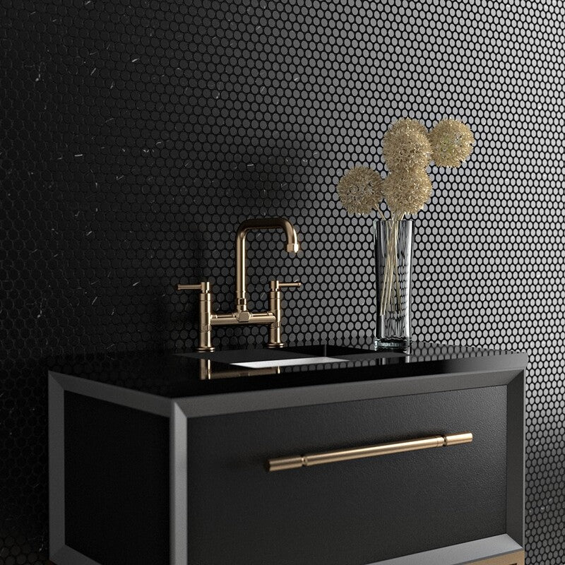 Modern black vanity with gold faucet, black penny round tile wall, clear vase with white flowers on vanity.