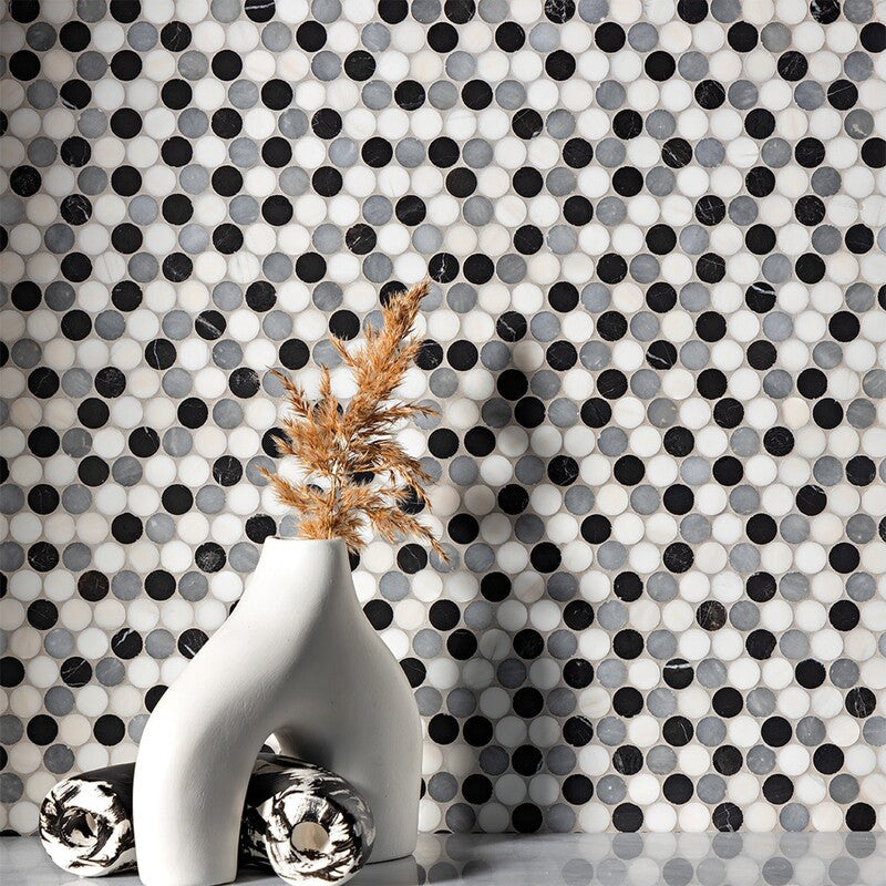 Black and white mosaic wall with modern vase holding pampas grass. Decorative spheres on smooth surface next to vase.