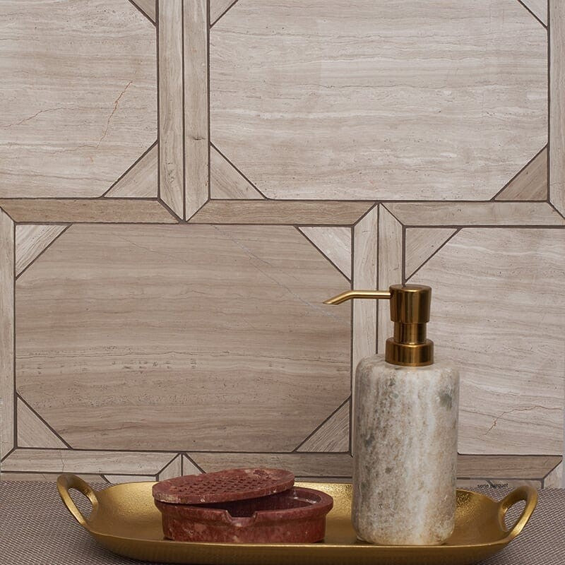 Bathroom scene with Haisa Light marble tiles in a parquet staggered joint mosaic pattern. Gold tray with marble soap dispenser and red soap dish.