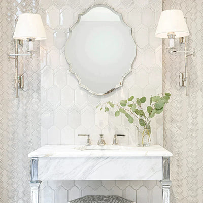 Elegant bathroom with intricate Breathe Moresque ceramic tiles, marble countertop, silver mirror, and sophisticated wall sconces.