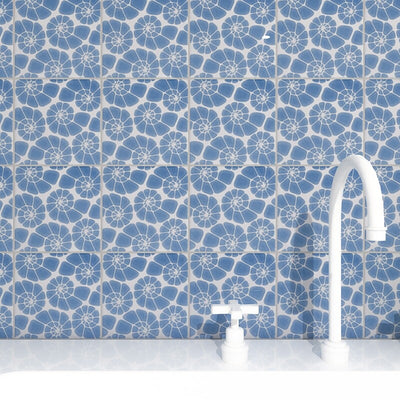 Blue and white floral tiles on wall, white countertop and faucet create clean, elegant kitchen or bathroom scene.