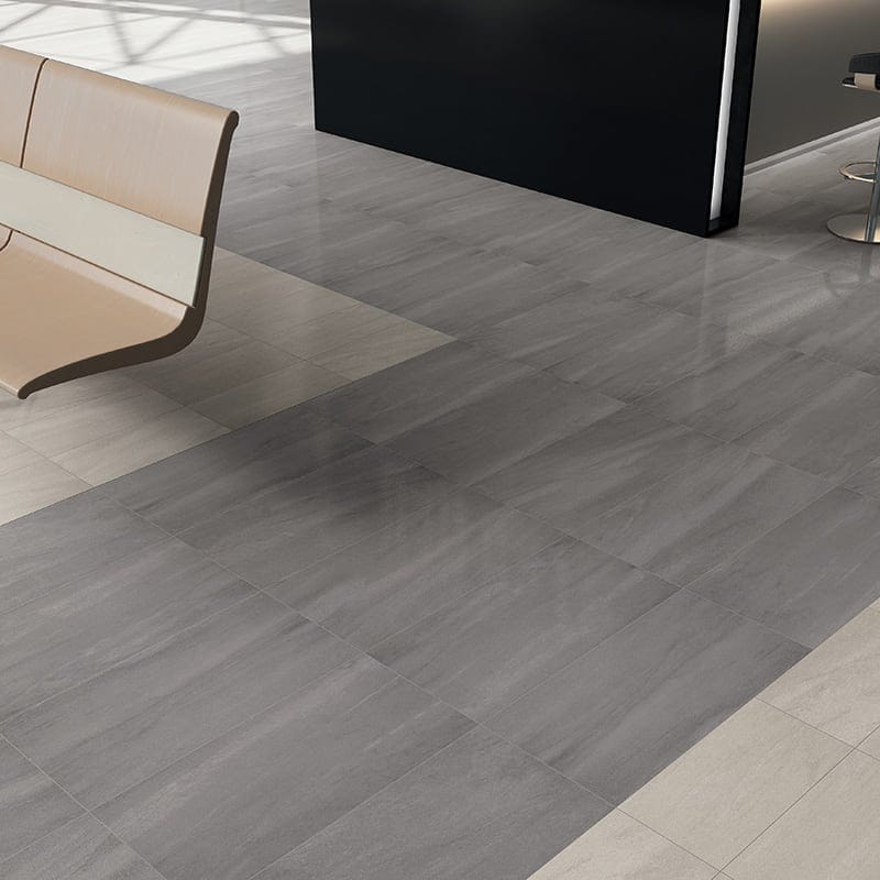 Modern interior with large grey porcelain tiles, mix of matte & polished finishes, minimalist bench, & sleek dark reception counter.