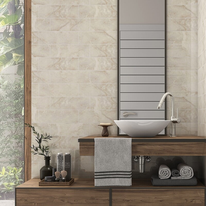 Stylish bathroom with white and grey marble tiles, wooden vanity, modern sink, tall mirror, towels, and decor. Bright with natural light and green view.