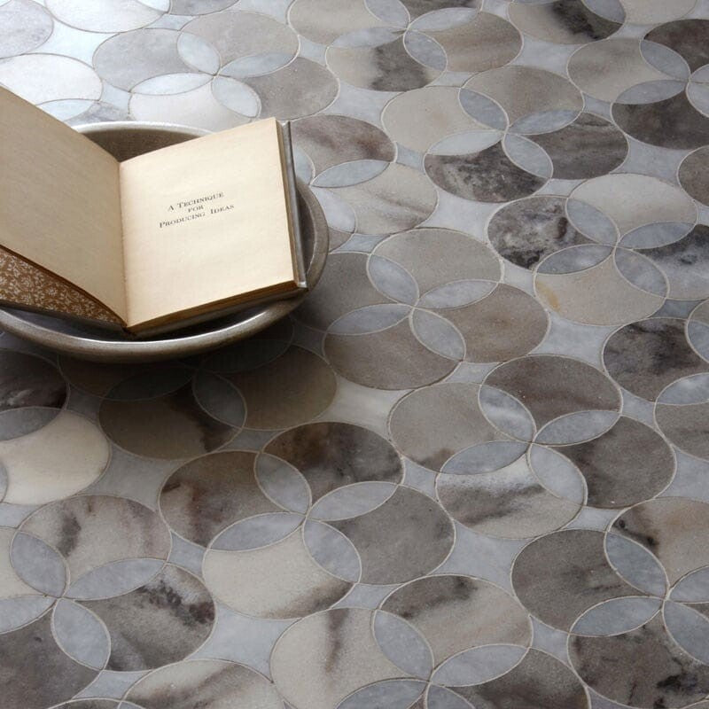 Marble tile floor with circular mosaic in grey and beige, bowl with open book as decor.