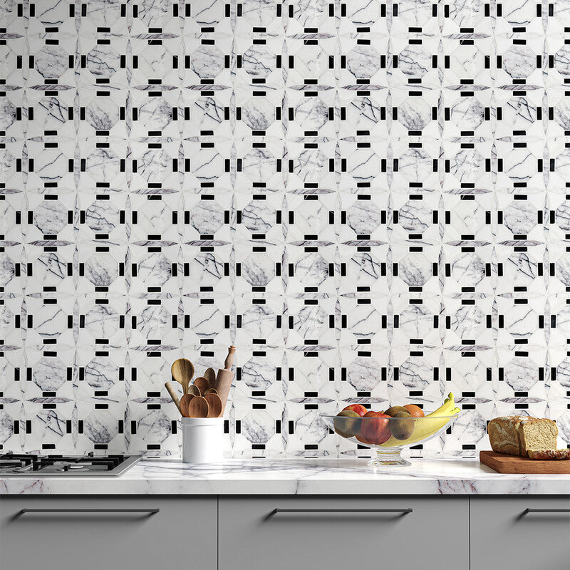 Kitchen scene with white marble backsplash, geometric black/white tiles, grey counter with fruit, wooden cutting board with bread, white utensil holder.