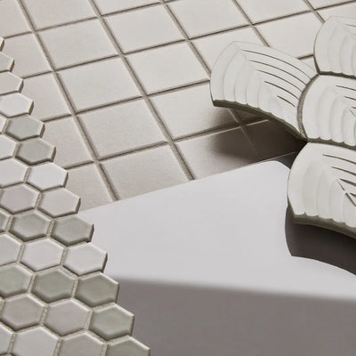 Minimalist bathroom design featuring Anatolia Soho Glazed Ceramic tiles with a subtle, geometric pattern in a calming gray hue, complemented by a contemporary round mirror and elegant bronze fixtures.