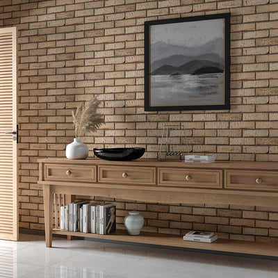 Living room with terracotta brick wall, wooden console table, black bowl, dried pampas grass, misty mountain artwork, books, and ceramic vase.