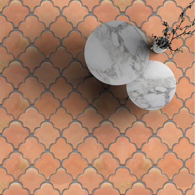 Terracotta tiles in interlocking pattern, warm orange hue. Two white marble tables with plants on top.