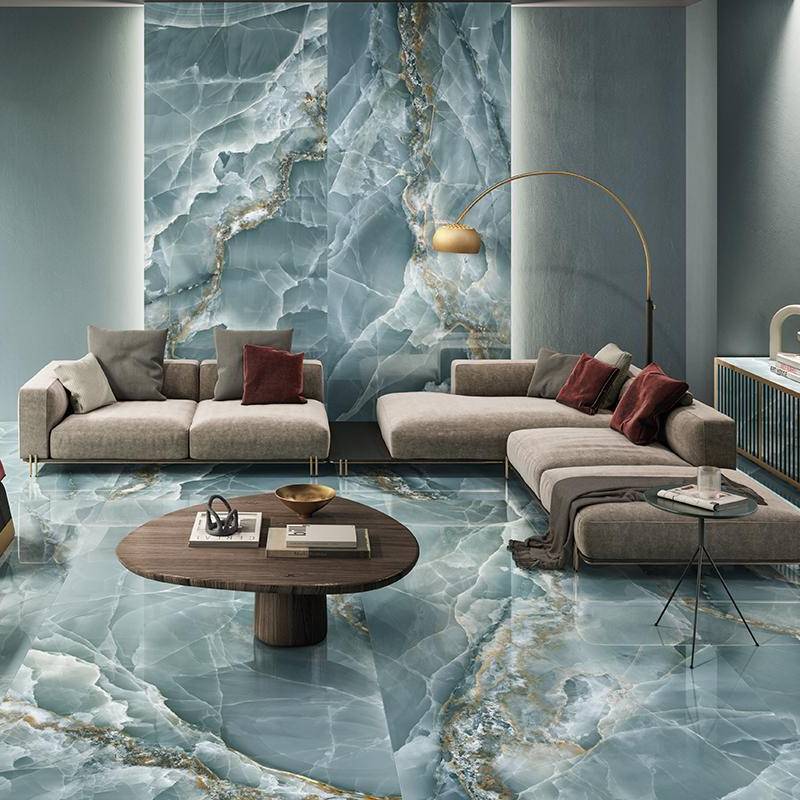 High-end living room featuring seamless onyx stone look porcelain tile on walls and floor, with elegant beige sofas, red cushions, and contemporary circular wooden coffee table.